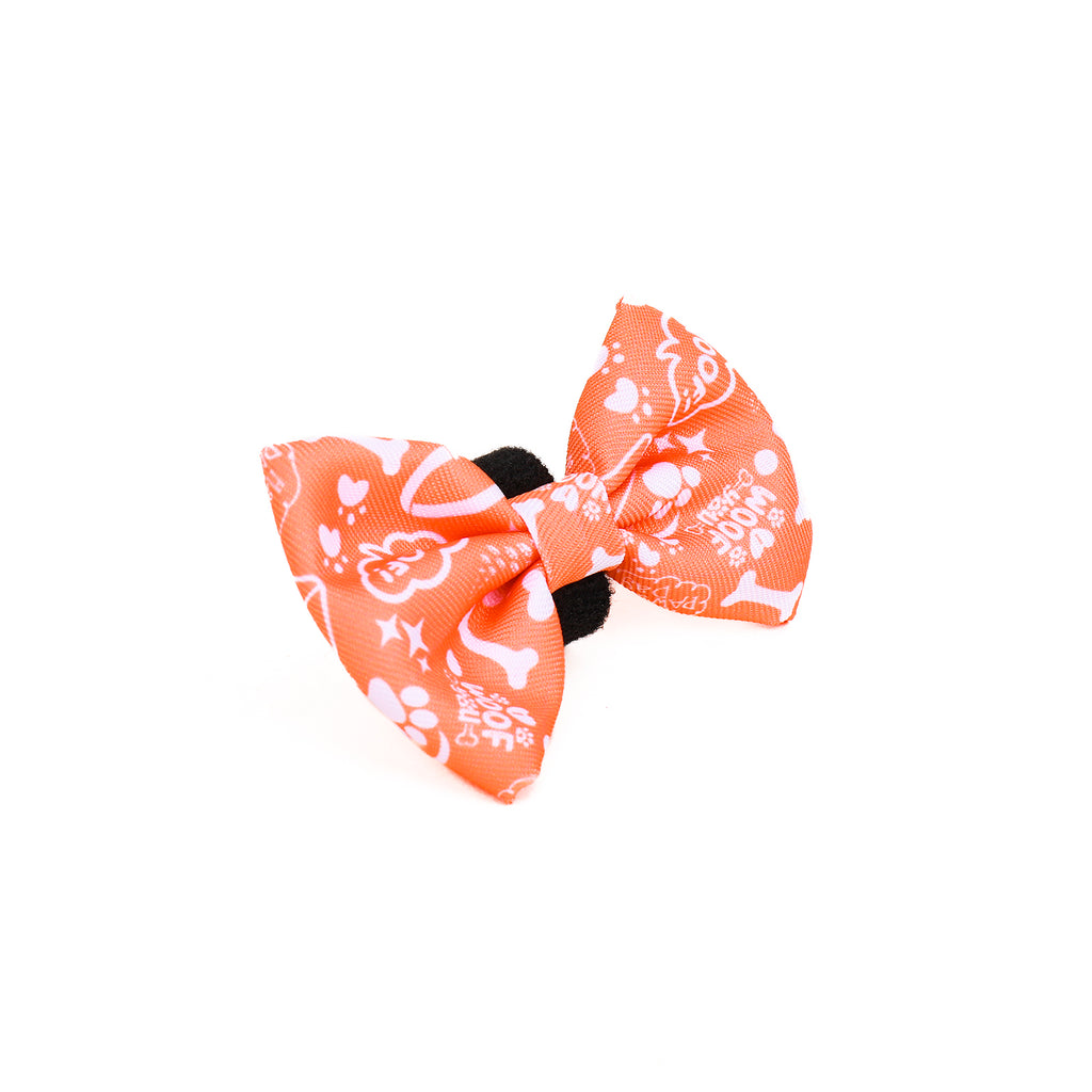 An orange bow tie for dogs with a paw print pattern on a white background.