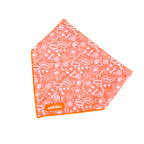 An orange dog bandana with a pattern of paw prints and text, displayed on a white background.