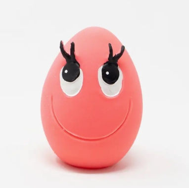Pink egg-shaped toy with googly eyes and black antennas on a white background
