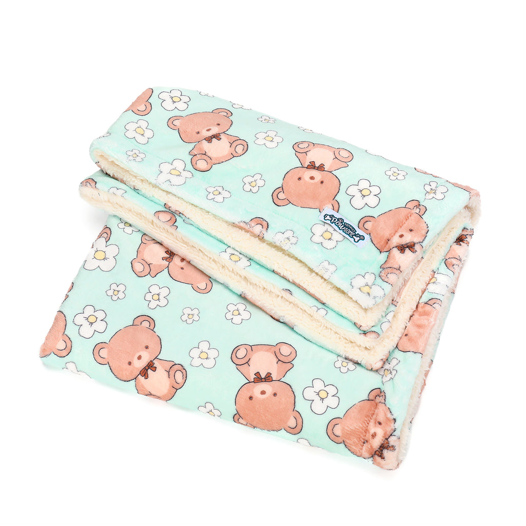 Folded blanket with teddy bear pattern on a light blue background