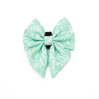 Light green bow with white patterns on a white background