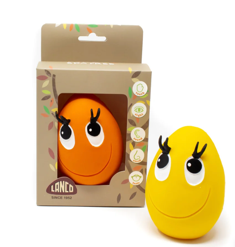 Orange and yellow toy with cartoon face design in front of its packaging