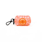 An orange dog poop bag holder with a pattern of paw prints and text, featuring a carabiner clip and a brand logo on the front.