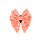 An orange dog sailor bowtie with a pattern that includes paw prints and illustrations.