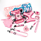 Pink pet accessory set including harnesses, leashes, and a bandana on a white background.