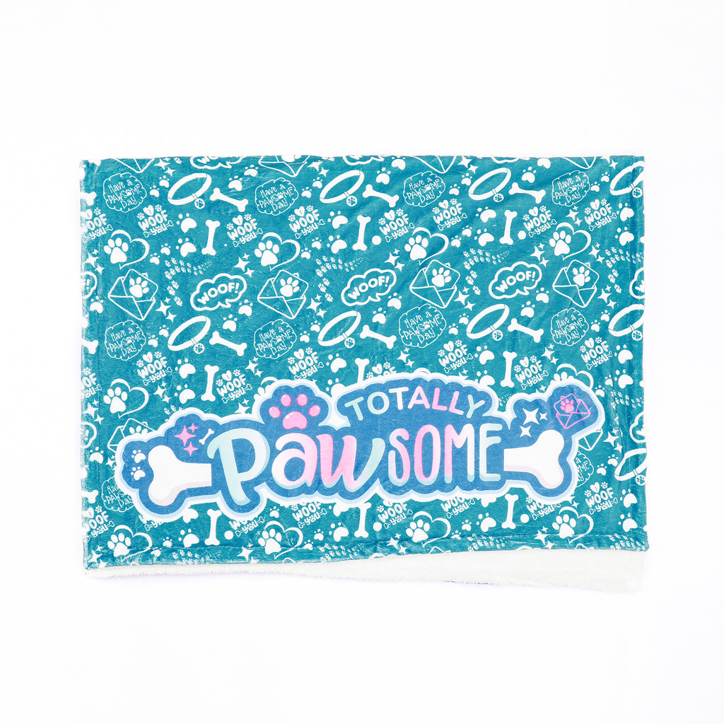 A teal fleece blanket with a pattern of paws and bones, and the text 'Totally Pawsome' across the center.