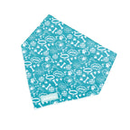 A teal dog bandana with a pattern of bones and paws, tied at the neck.